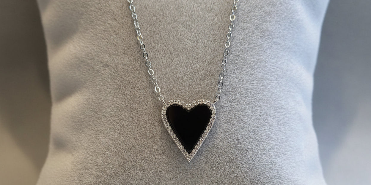A sterling silver heart-shaped necklace with a chain, surrounded by cubic zirconia decorations in a layered design.
