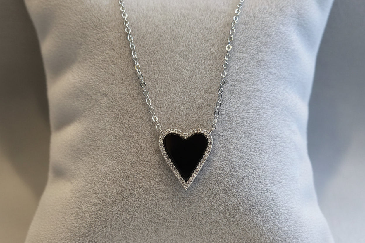 A sterling silver heart-shaped necklace with a chain, surrounded by cubic zirconia decorations in a layered design.