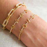 Gold bracelets with 'I love you' on a wrist against a neutral background