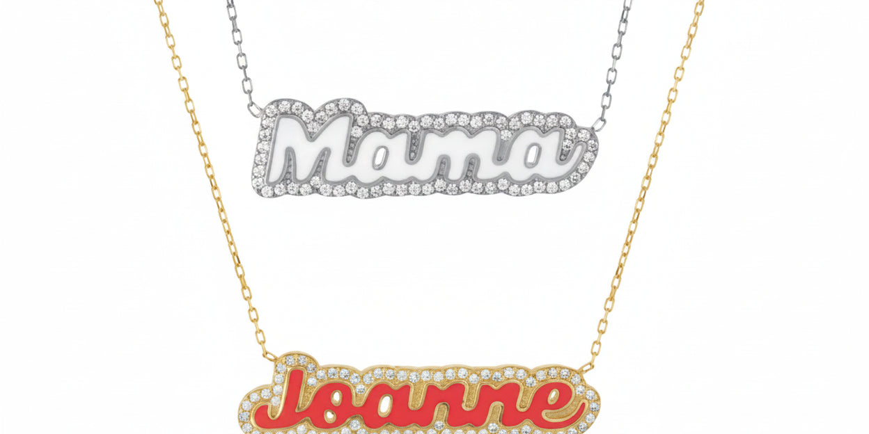 Two enamel name necklaces, one in silver with cubic zirconia surrounding the name 'Maria', and one in gold with cubic zirconia surrounding the name 'Joanne'.
