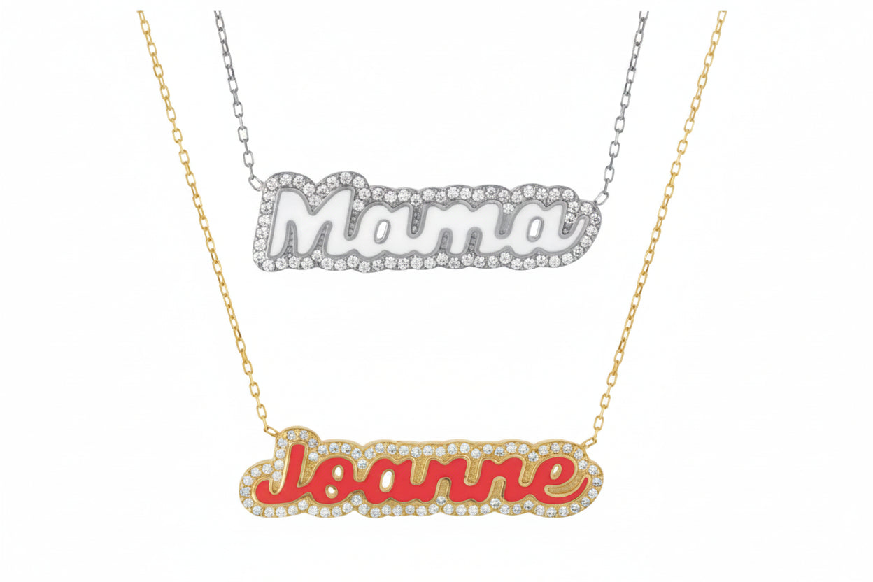 Two enamel name necklaces, one in silver with cubic zirconia surrounding the name 'Maria', and one in gold with cubic zirconia surrounding the name 'Joanne'.